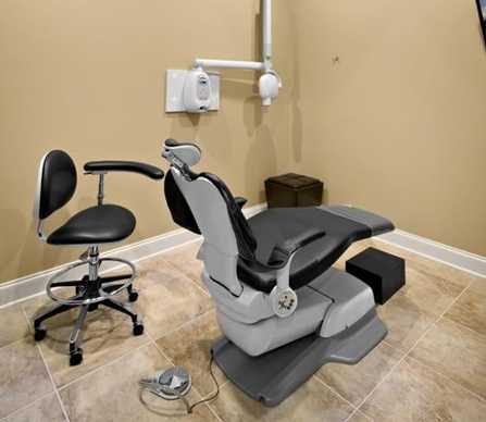 Modern dental operatory with chair, stool, and equipment in clinical treatment room