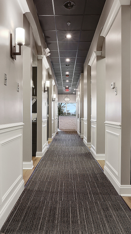 Modern dental office hallway with white walls, dark flooring, and recessed lighting.