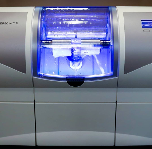 Modern dental lab equipment with blue lighting illuminated inside chamber.