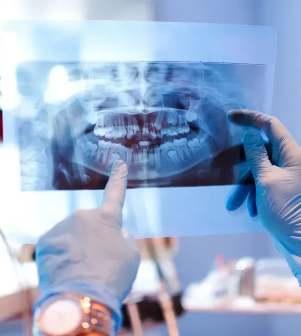 Dentist examining dental X-ray against light box in clinical setting.