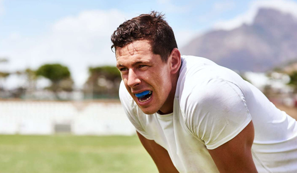 Man in white shirt exercising outdoors with mountains in background, appearing energetic and healthy.